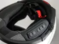 Detalle del interior de un casco modular, mostrando el proceso para instalar intercomunicador. Botones de control visibles.
