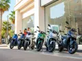 Pareja sonriente junto a varias motos eléctricas modernas, ideales para un plan renove moto.