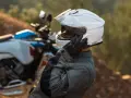 Motociclista ajustándose su casco modular silencioso blanco, listo para la aventura.
