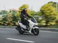 Persona conduce moto blanca con carnet B, disfrutando del paisaje borroso.