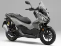 Scooter gris Honda ADV 160 con parabrisas alto y asiento doble.
