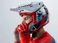 Hombre con casco de moto para usar con gafas graduadas, guantes rojos y jersey deportivo.