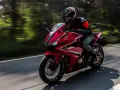 Motociclista en moto deportiva roja, disfrutando de la carretera con potencia máxima A2.