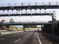 Un pórtico de peaje automático en España. Los coches circulan por la autopista bajo una estructura metálica con antenas.