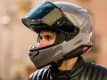 Hombre con casco de moto gris brillante. ¿Cuánto pesa un casco de moto? Este modelo parece ligero y aerodinámico.