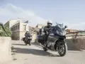 Dos motociclistas en sus Benelli 1200 GT recorren un pueblo soleado.