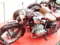 Moto Derbi clásica con sidecar, color burdeos, con asientos de cuero marrón y detalles cromados.