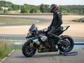 Piloto con talla mono moto listo para competir en circuito.