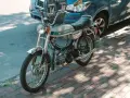 Ciclomotor antiguo Puch Magnum II plateado, listo para matricular. Aparcado junto a un coche azul en la acera.