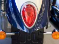 Detalle de la parte trasera de una moto azul y blanca, con intermitentes naranjas y luz roja. Podría ser una multa por llevar luces led moto.