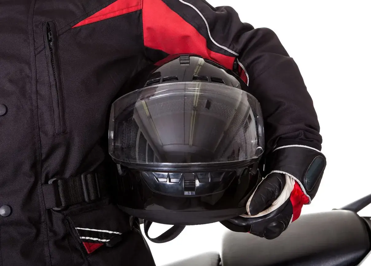 Motociclista con chaqueta negra y roja, guantes y casco con visor transparente. El pinlock casco garantiza una visión clara.