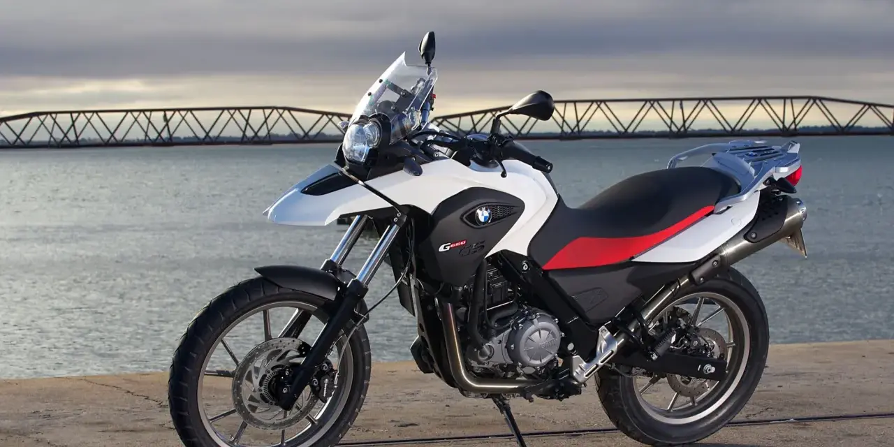 Moto BMW G 650 GS, ideal para el carnet A2, aparcada junto a un puente y el mar.