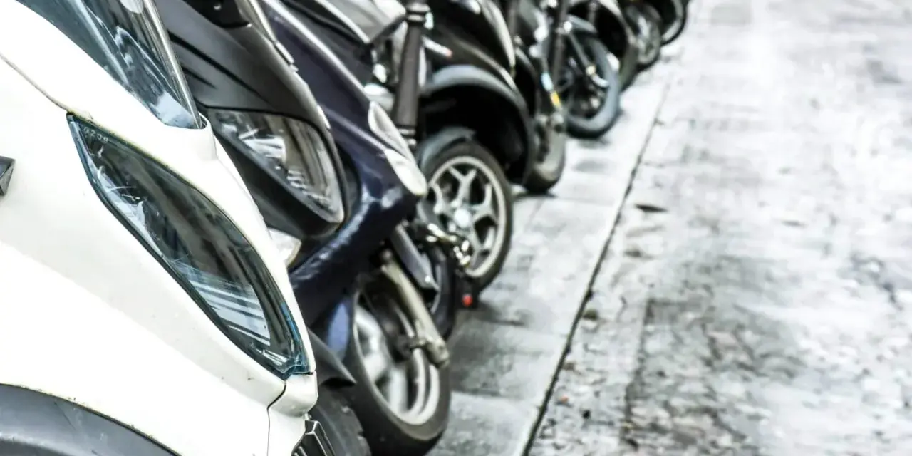 Una fila de motos aparcadas en la acera. Se puede aparcar la moto en la acera, facilitando el tránsito peatonal.