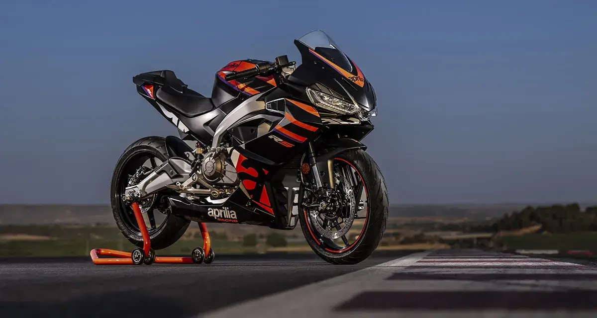 Aprilia RS 457 ficha técnica: una deportiva negra con detalles naranjas y rojos, lista para la acción en pista.