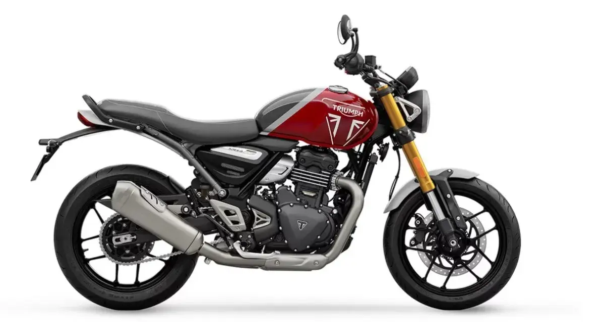 Una moto Triumph roja y gris, un ejemplo de motos neo retro, con horquilla dorada y escape plateado, lista para la aventura.