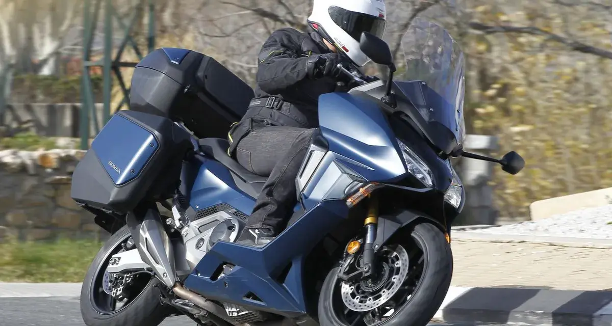 Motociclista en Honda Forza 750 azul con maletas, ideal para viajes. Conoce su honda forza 750 ficha técnica.