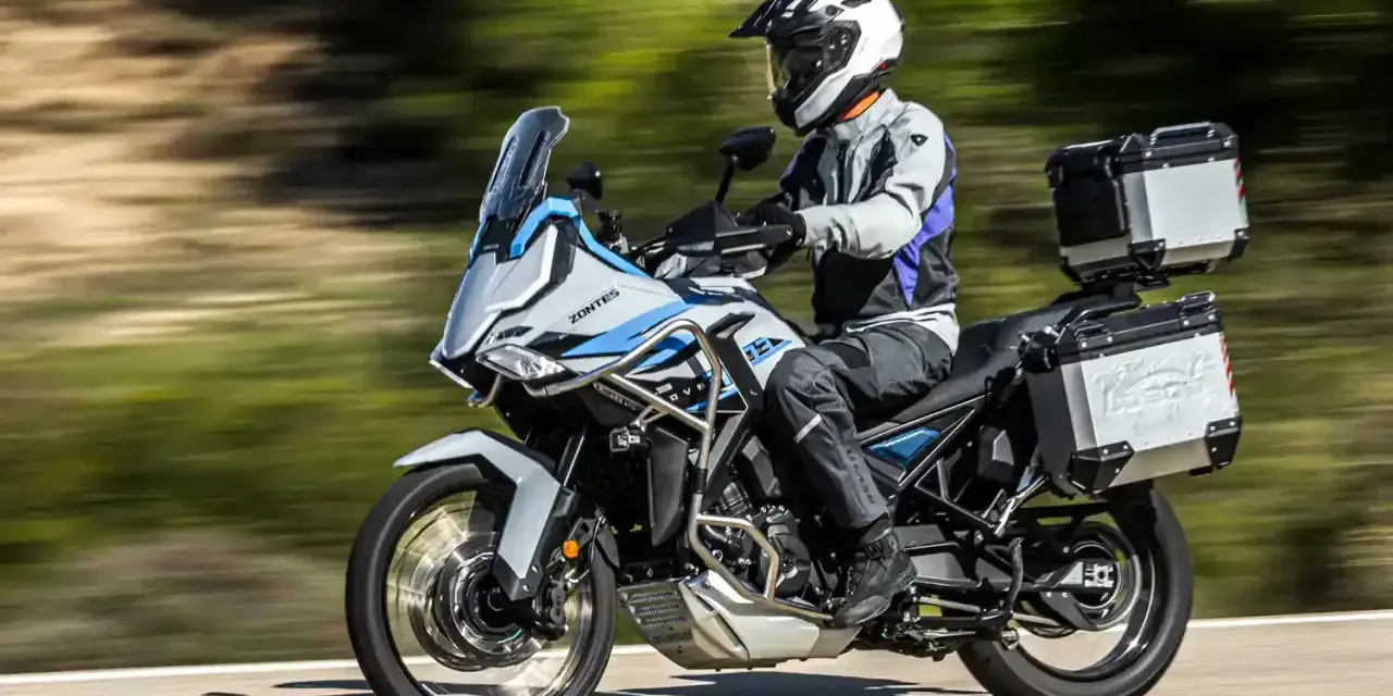 Motociclista con casco blanco y equipo de aventura sobre una moto Zontes, lista para explorar caminos. Motos adventure A2 perfectas para tu próxima travesía.
