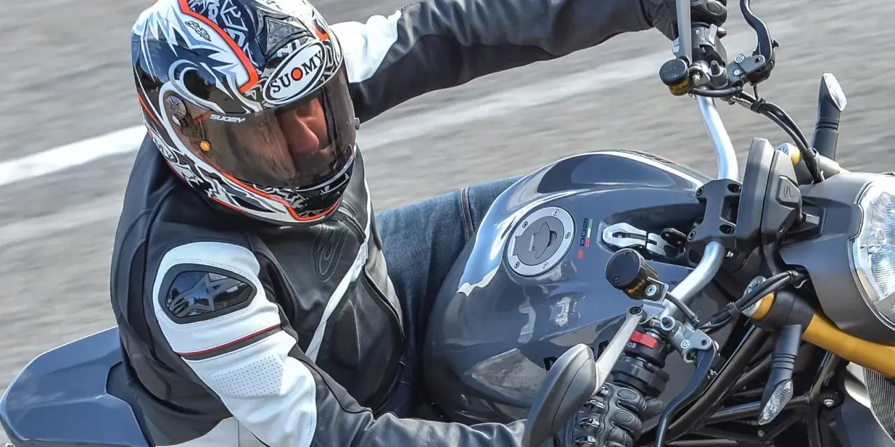 Motociclista con casco Suomy, con diseño llamativo, en una moto deportiva. Las opiniones sobre cascos Suomy son positivas.