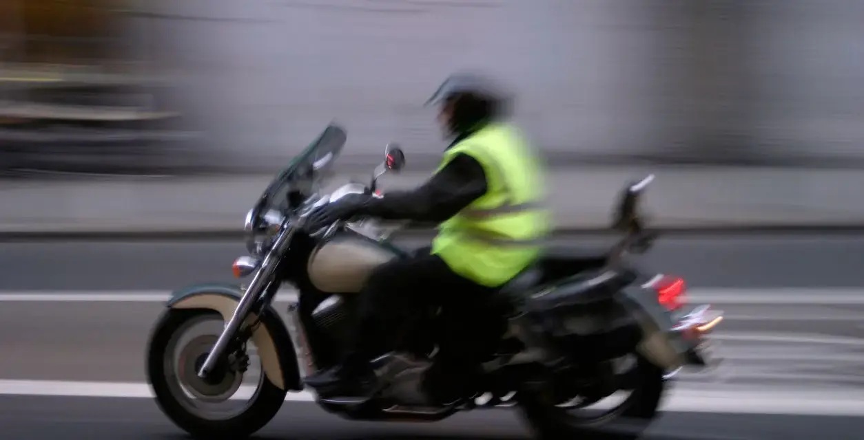 Motociclista con chaleco reflectante amarillo brillante, cumpliendo la norma de que es obligatorio llevar chaleco reflectante en la moto.