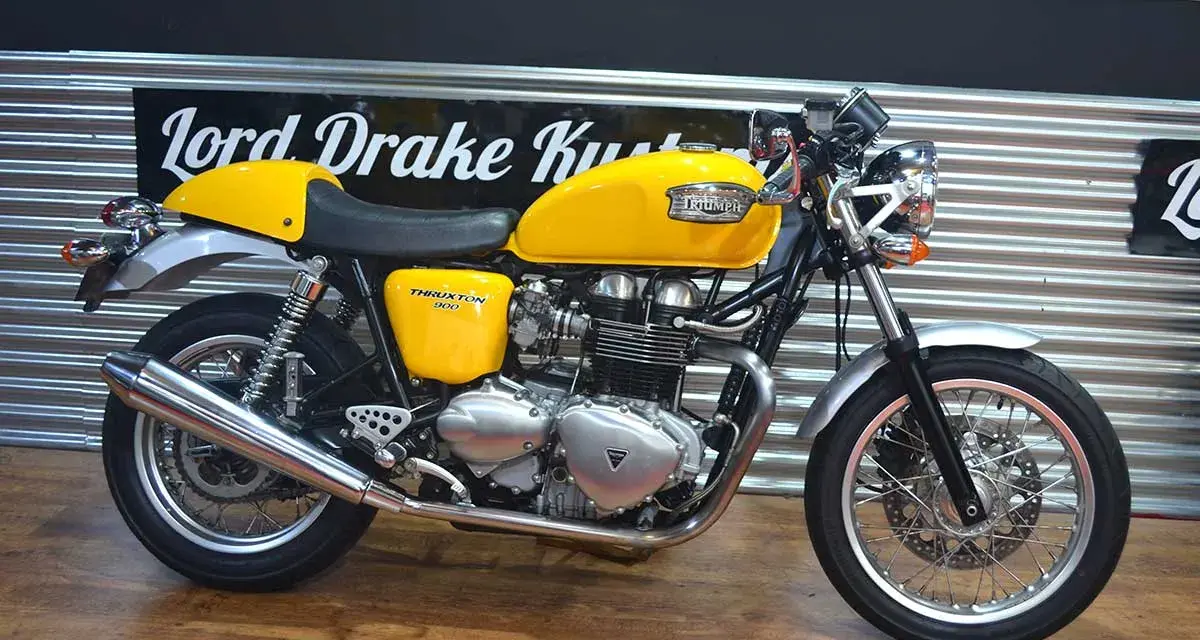 Motocicleta Triumph Thruxton 900 amarilla, estilo café racer, lista para la carretera.