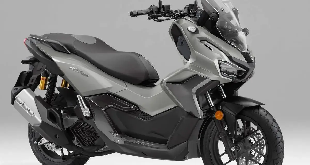 Scooter gris Honda ADV 160 con parabrisas alto y asiento doble.