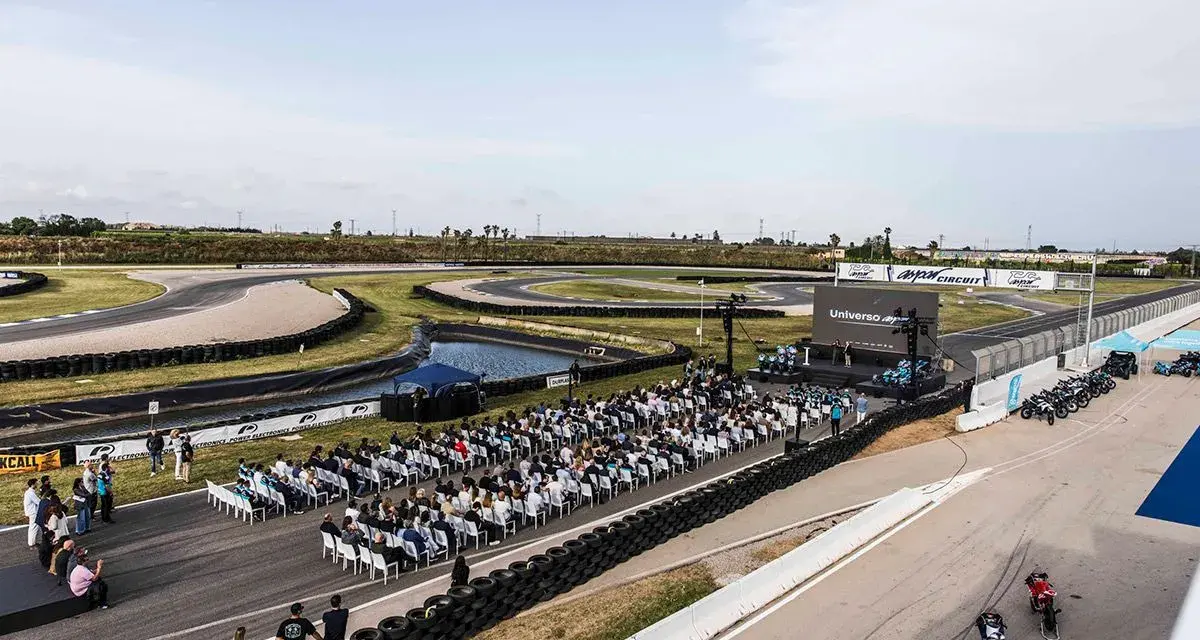 Evento en el aspar circuit con público sentado frente a un escenario. Motos alineadas en la pista.