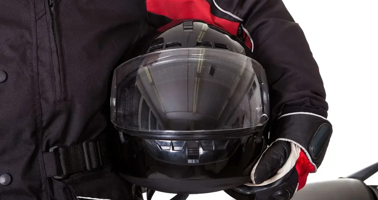 Motociclista con chaqueta negra y roja, guantes y casco con visor transparente. El pinlock casco garantiza una visión clara.