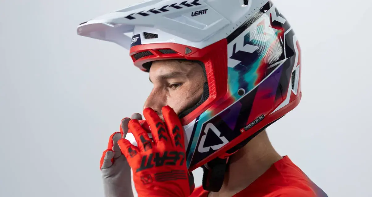 Hombre con casco de moto para usar con gafas graduadas, guantes rojos y jersey deportivo.