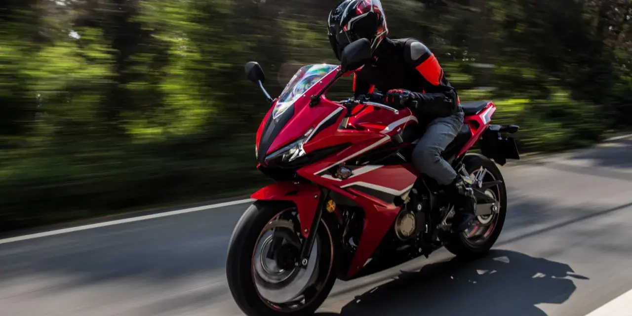 Motociclista en moto deportiva roja, disfrutando de la carretera con potencia máxima A2.