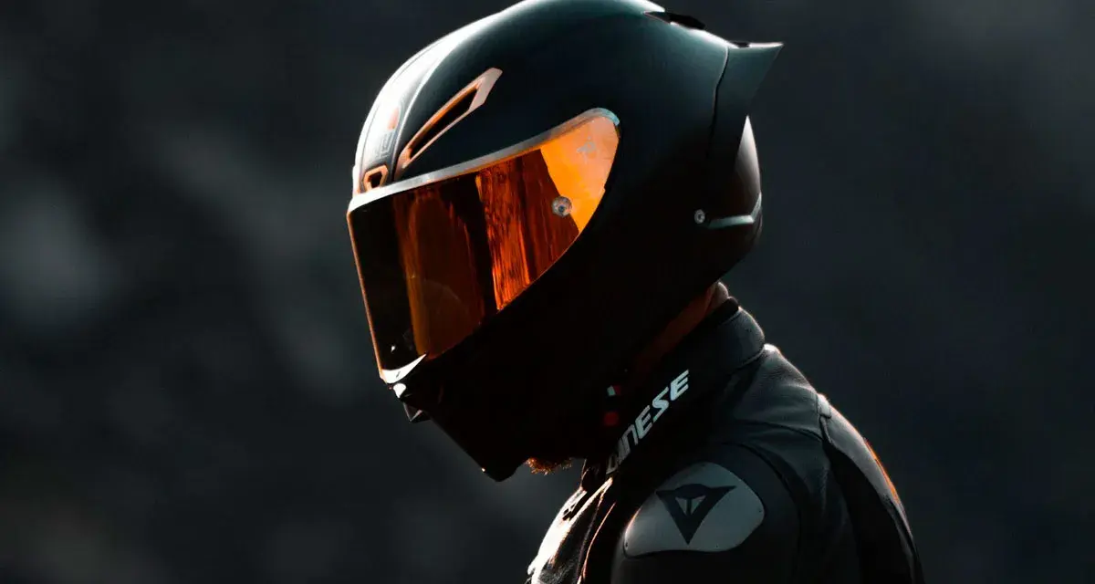 Motociclista con su primer casco de moto, visera naranja reflejando la luz.