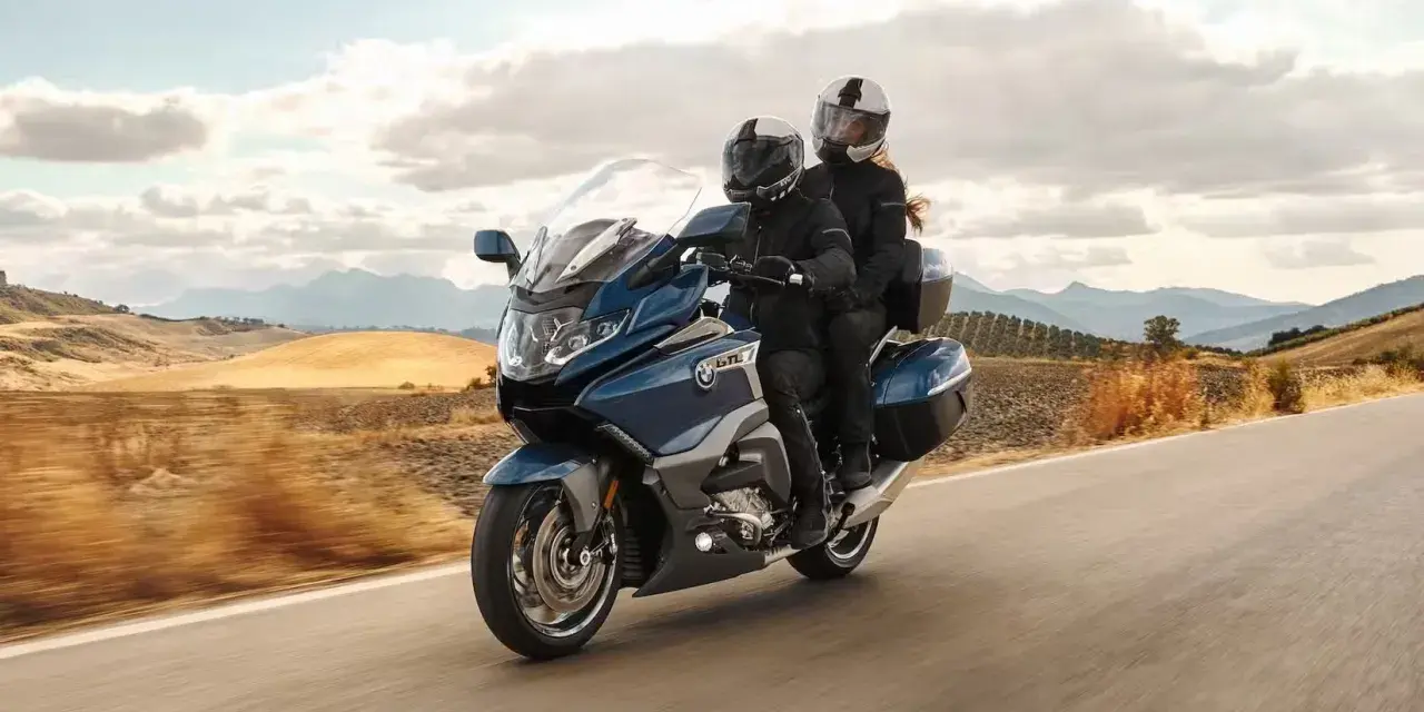 Pareja disfrutando de un viaje en moto cómoda por un paisaje rural.