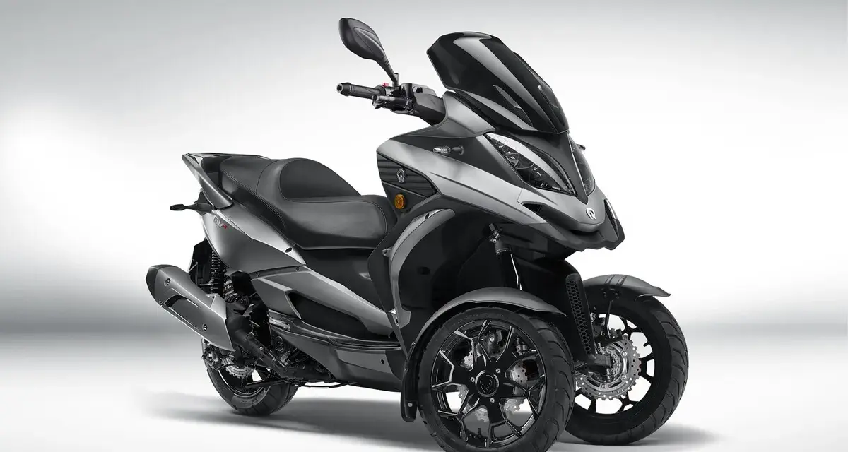 Triciclo gris moderno, estilo deportivo, con tres ruedas. El **Quadro QV3** es un vehículo ágil y seguro, ideal para sortear el tráfico urbano sin **problemas**.