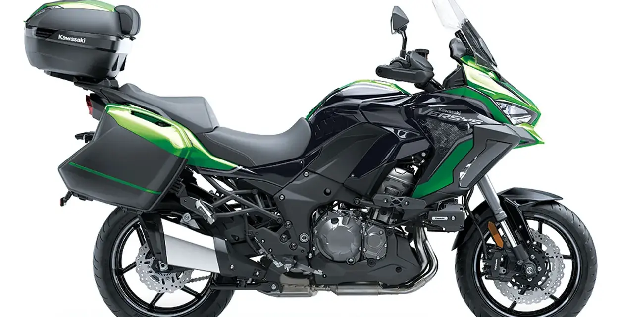 Una moto crossover Kawasaki Versys negra y verde, lista para la aventura con maletas laterales y baúl.