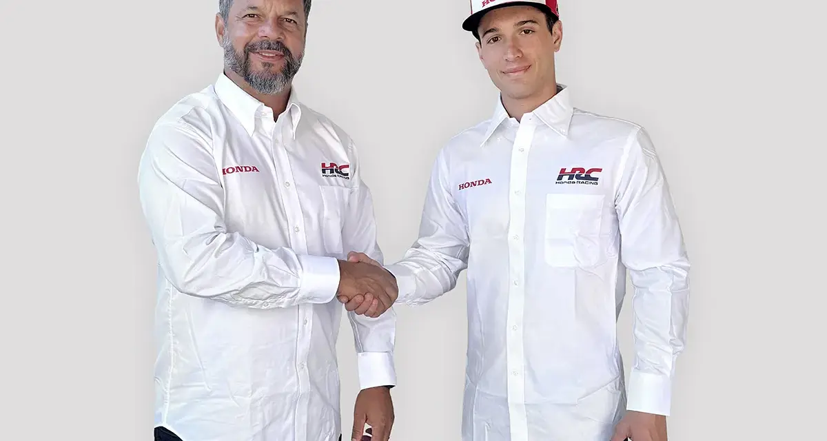 Dos hombres con camisas blancas de Honda y HRC Racing se dan la mano. Uno lleva una gorra de Honda.