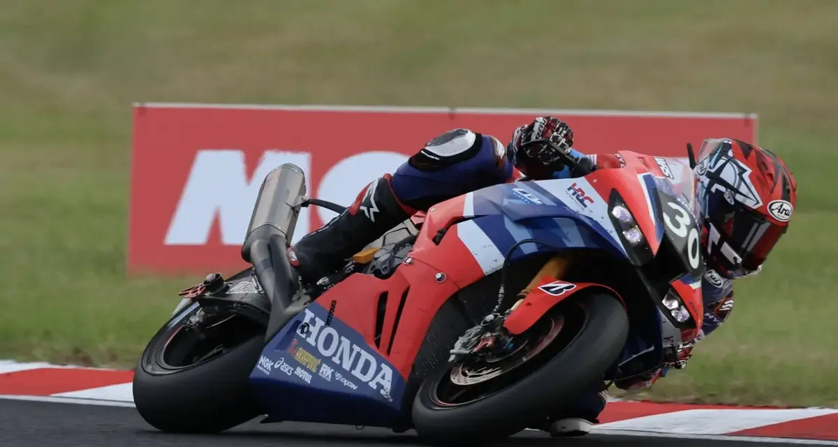 Piloto en moto Honda roja y azul inclinado en curva durante las 8 horas de Suzuka.