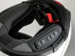 Detalle del interior de un casco modular, mostrando el proceso para instalar intercomunicador. Botones de control visibles.