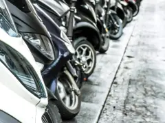 Una fila de motos aparcadas en la acera. Se puede aparcar la moto en la acera, facilitando el tránsito peatonal.