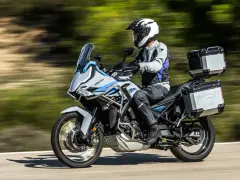 Motociclista con casco blanco y equipo de aventura sobre una moto Zontes, lista para explorar caminos. Motos adventure A2 perfectas para tu próxima travesía.