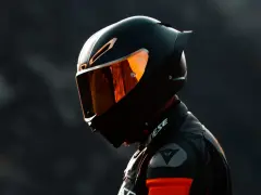 Motociclista con su primer casco de moto, visera naranja reflejando la luz.