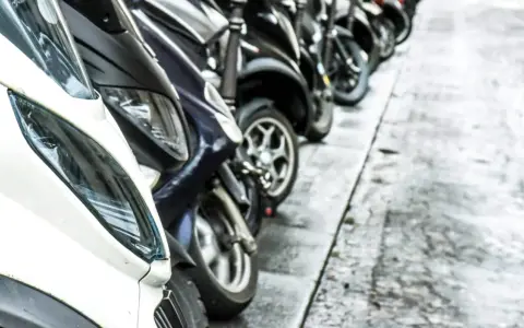 Una fila de motos aparcadas en la acera. Se puede aparcar la moto en la acera, facilitando el tránsito peatonal.
