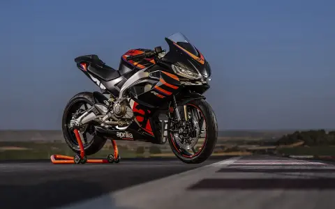Aprilia RS 457 ficha técnica: una deportiva negra con detalles naranjas y rojos, lista para la acción en pista.