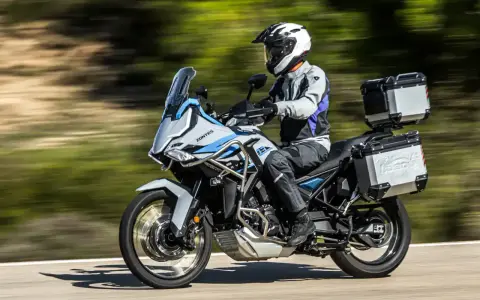 Motociclista con casco blanco y equipo de aventura sobre una moto Zontes, lista para explorar caminos. Motos adventure A2 perfectas para tu próxima travesía.