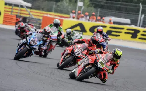 Motociclistas compiten en una carrera, con el número 65 en primer plano. El sbk calendario se acerca.