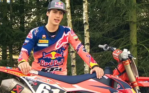 Jorge Prado, piloto de motocross, posa con su moto KTM en un bosque.