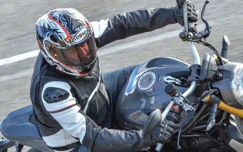 Motociclista con casco Suomy, con diseño llamativo, en una moto deportiva. Las opiniones sobre cascos Suomy son positivas.