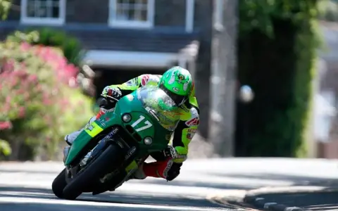 Victor López compite en la Isla de Man con su moto verde número 17, inclinado en una curva cerrada.
