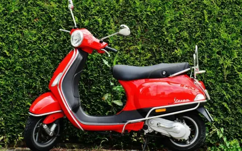 Scooter roja aparcada frente a un seto verde. Ideal para entender las diferencias carnet a1 y a2.