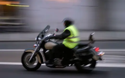 Motociclista con chaleco reflectante amarillo brillante, cumpliendo la norma de que es obligatorio llevar chaleco reflectante en la moto.