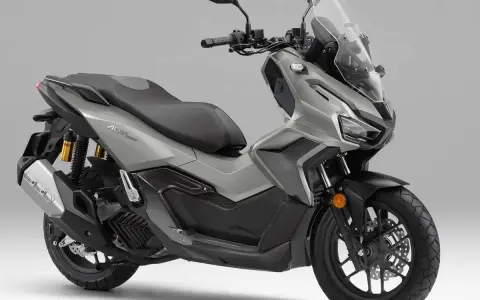 Scooter gris Honda ADV 160 con parabrisas alto y asiento doble.
