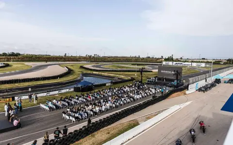 Evento en el aspar circuit con público sentado frente a un escenario. Motos alineadas en la pista.